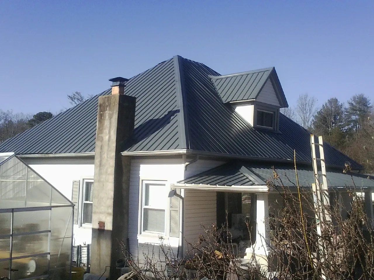 Dark blue standing seam metal roof on a white farmhouse with dormer — Slate & Tile Roof Repair by Roofing Brothers in Sandy