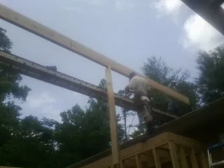 Carpenter setting a ridge beam over a new addition frame — Ice Dam Removal by Roofing Brothers in Sandy