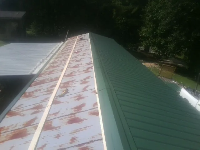 Old rusted panels beside newly installed green metal roofing — Wind Damage Roof Repair by Roofing Brothers in Sandy