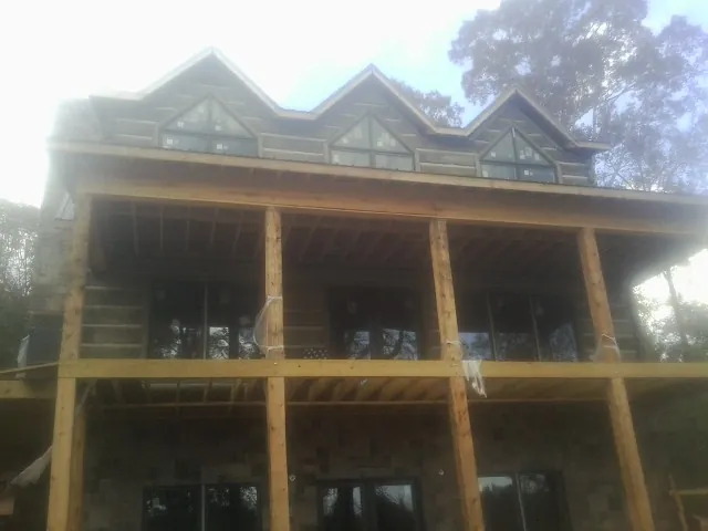 Dormers and porch framing on a large log home under construction — Roof Coating work by our crew in Sandy