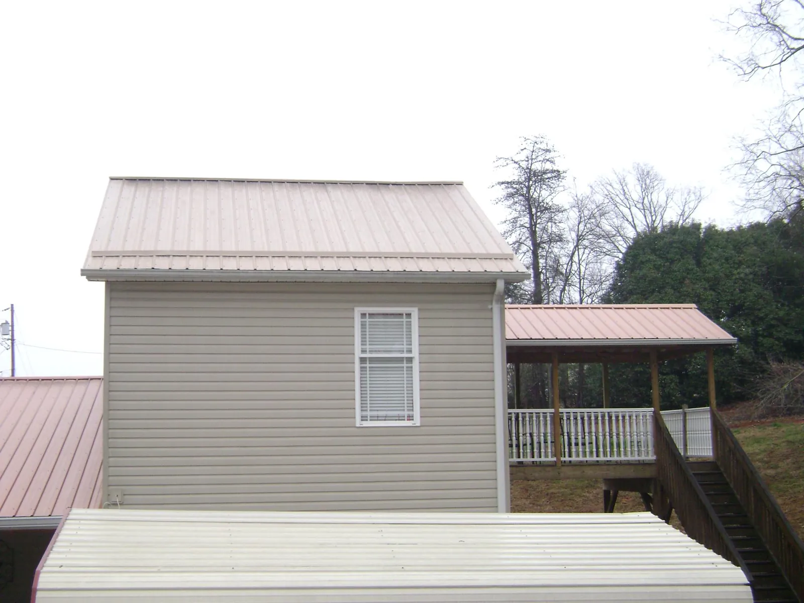 Tan metal roofs on a two story addition and attached porch, from a Roof Replacement job in Sandy