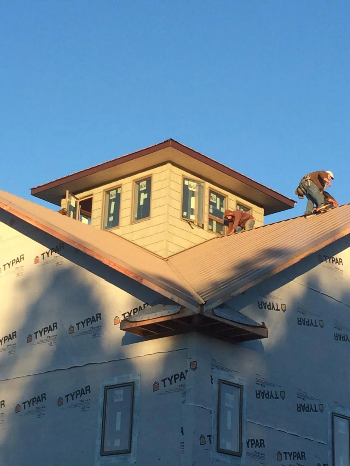 Roofers working around a rooftop cupola on a new metal roof at sunset — Roof Waterproofing in Sandy by Roofing Brothers